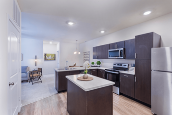 A modern kitchen with dark wood cabinets and stainless steel appliances.